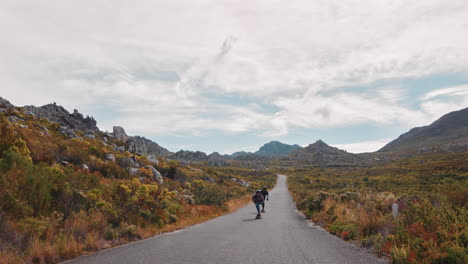 Felices-Amigos-Multiétnicos-Haciendo-Longboard-Juntos-Montando-Rápido-En-Una-Hermosa-Carretera-Rural-Disfrutando-De-Unas-Relajadas-Vacaciones-De-Verano-Navegando-Usando-Patineta-En-Cámara-Lenta