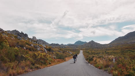 felices amigos multiétnicos haciendo longboard juntos montando rápido en una hermosa carretera de campo disfrutando de unas vacaciones de verano relajadas navegando usando skateboard en cámara lenta