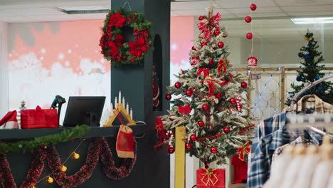árbol de navidad bellamente decorado en la tienda de ropa listo para difundir la alegría navideña a los clientes visitantes que buscan comprar regalos. xmas adorna la boutique de moda en el centro comercial durante la temporada de vacaciones de invierno