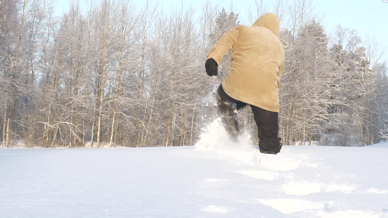 hombre con ropa de invierno camina en la nieve del bosque profundo