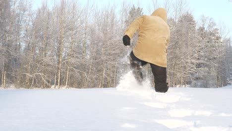 Man-in-winter-clothes-walks-off-in-deep-forest-snow