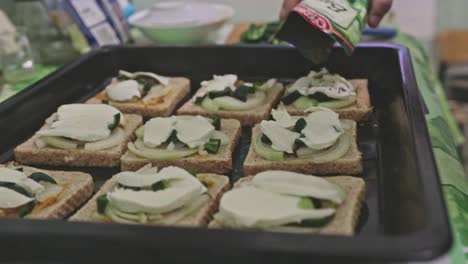 adding herbs to toasts on a tray ready to be baked