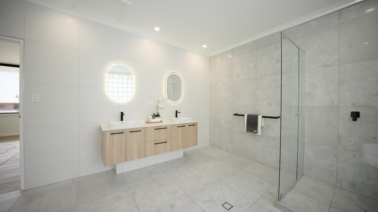 Amplio y lujoso baño principal moderno en suite con tocador doble, muebles de madera y espejos circulares