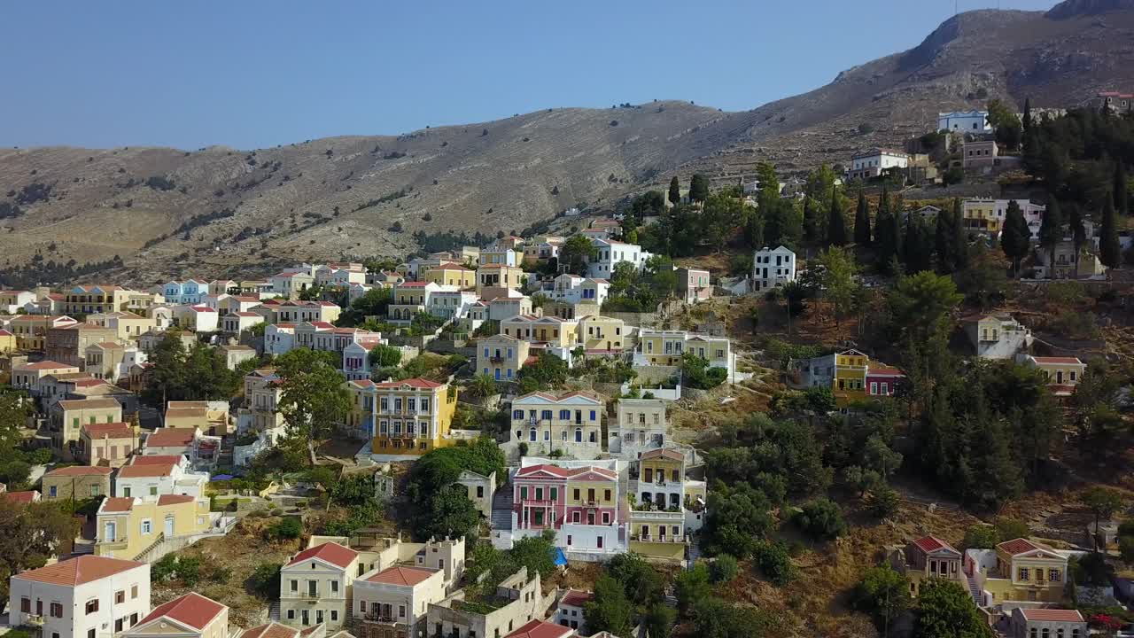 Aerial view of the small greek town with colourful homes at the island Symi. Drone moving from left to right