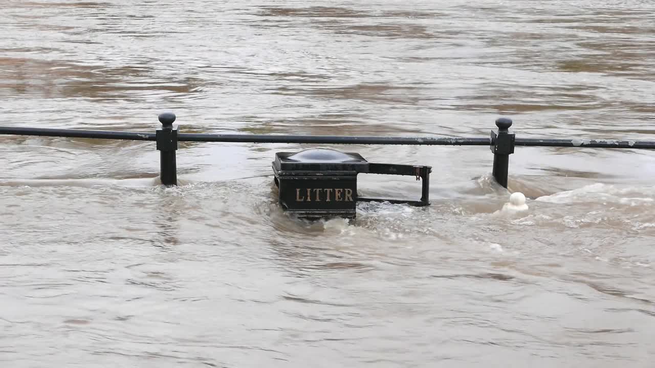 The River Severn overflowing its banks and covering railings and a litter bin