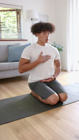 vertical video: young man meditating on yoga mat at home, practicing mindfulness and relaxation