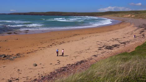 People-walk-along-a-beautiful-beach-on-the-coast-of-Southern-Wales