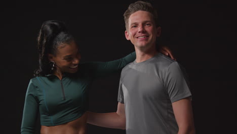 Studio-Portrait-Of-Smiling-Athletic-Couple-Or-Friends-In-Fitness-Clothing-Training-Shot-Against-Black-Background-1