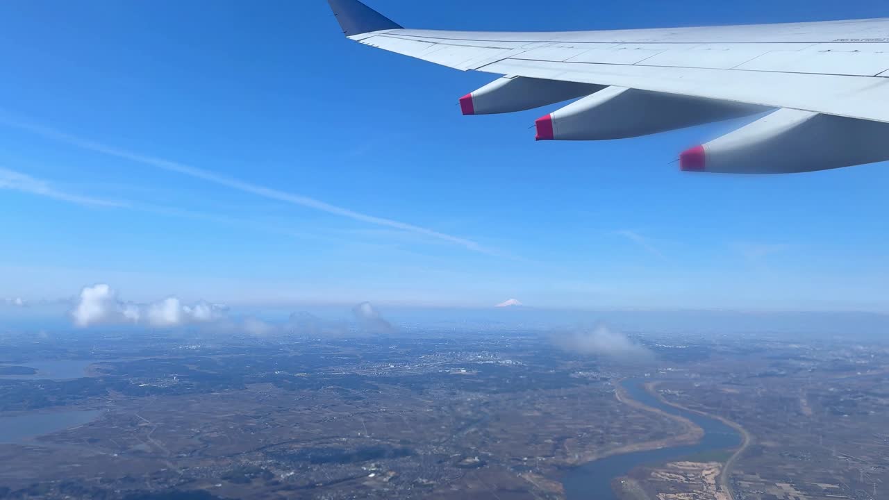 Luftfoto fra flyvindue over bybillede med klar blå himmel.