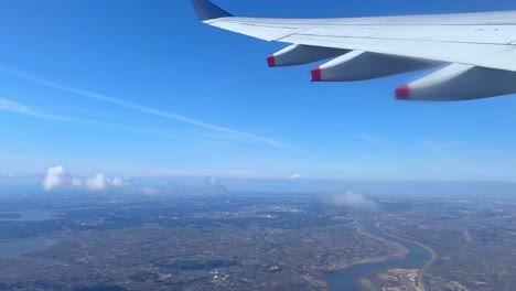 Aerial-view-from-airplane-window-over-cityscape-with-clear-blue-sky