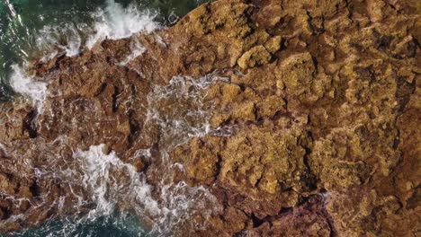 Seawaves-hitting-rocky-coastline-of-Tenerife,-aerial-top-down-ascend-view