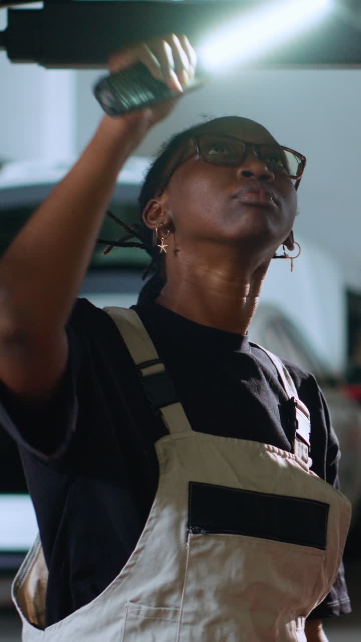 Vertical video Engineer inspects car on overhead lift