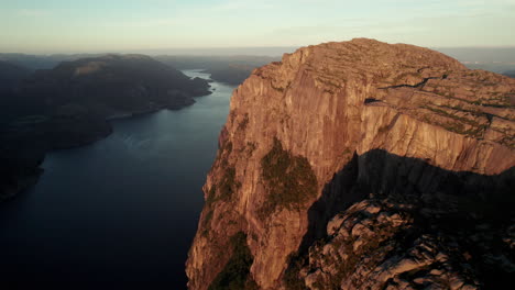 breathtaking aerial view of an impressive cliff in norway, sunrise atmosphere in the lysefjorden, preikestolen, pulpit rock, some tourists are gathered on the rock