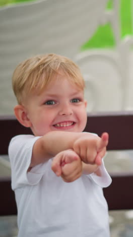 un niño alegre extiende su mano juguetón, sonriendo de emoción. a su lado, su hermano mayor, con gafas, se sienta y se une a él extendiendo su mano también