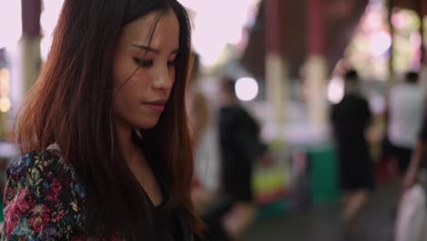 Young Asian woman smelling a fragrance bottle at an outdoor market