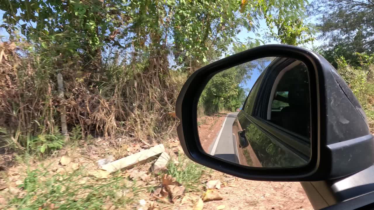 espejo lateral del coche que refleja el viaje por carretera rural