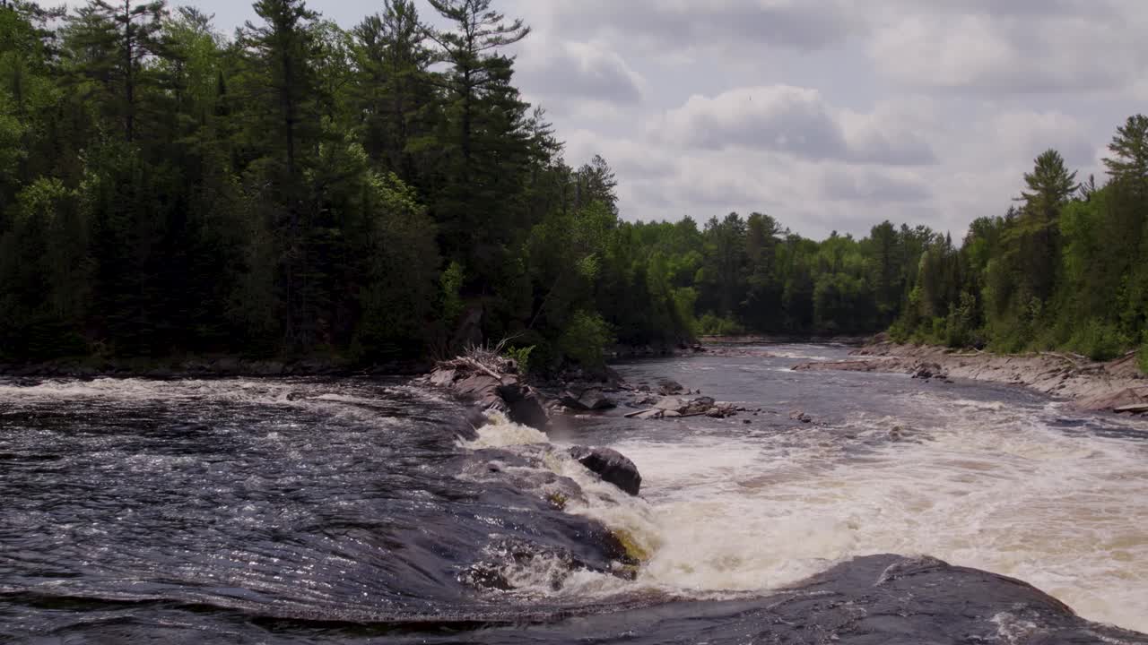 Droneflyvning over Gatineau-flodens hvide vand og strømhvirvler, der flyder gennem den barske canadiske vildmark