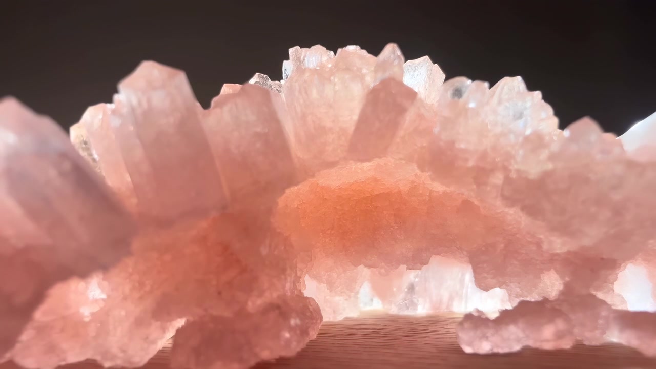Encuadre central de un grupo de cristales de cuarzo rosa descansando sobre una superficie de madera