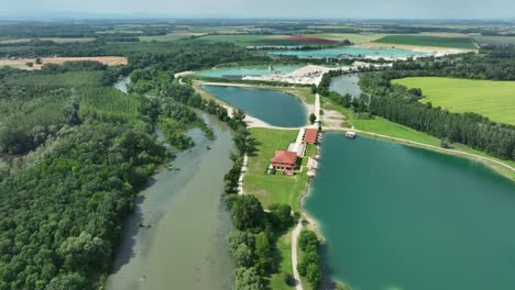 aerial ascending drone footage of the small danube river revealing gravel pits, emerald lakes and fields below