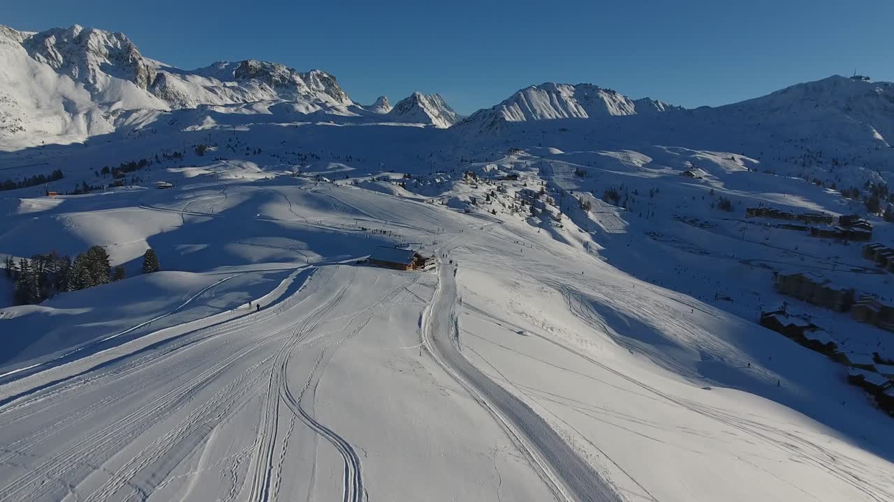 Ripresa veloce con drone in volo sopra La Plagne nelle Alpi francesi. Giornata soleggiata e innevata.
