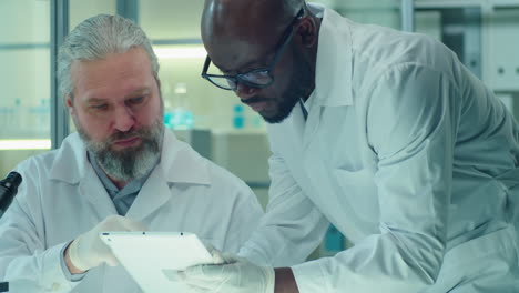 Multiethnic Scientists Using Tablet and Talking in Lab