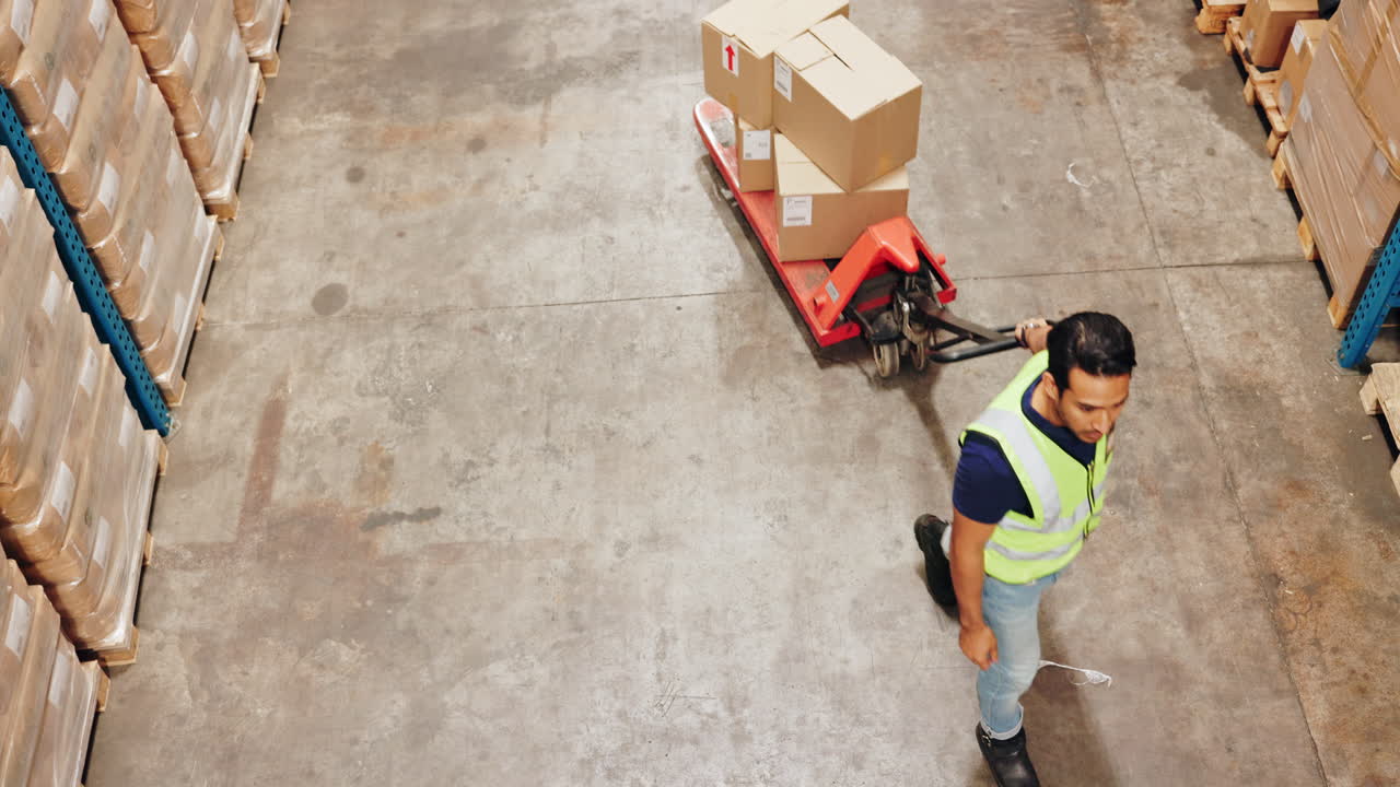 Worker moving boxes with a pallet jack in a warehouse