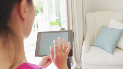 Asian-woman-using-tablet-with-smart-home-interface-in-bedroom,-in-slow-motion