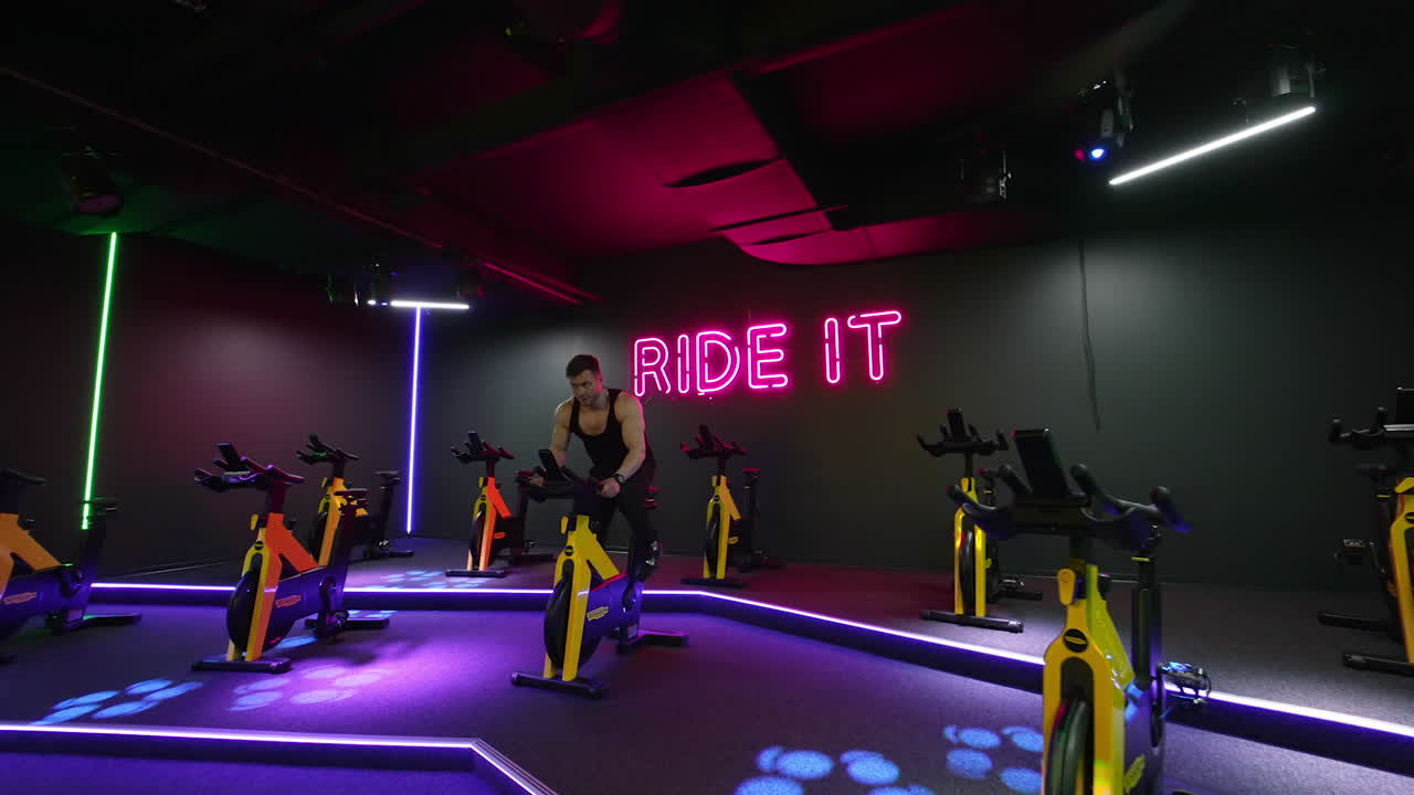 Young man working out on bike. Attractive man riding exercise bike in the gym