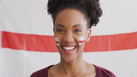 video de una emocionada mujer afroamericana con bandera de inglaterra viendo el partido en la televisión