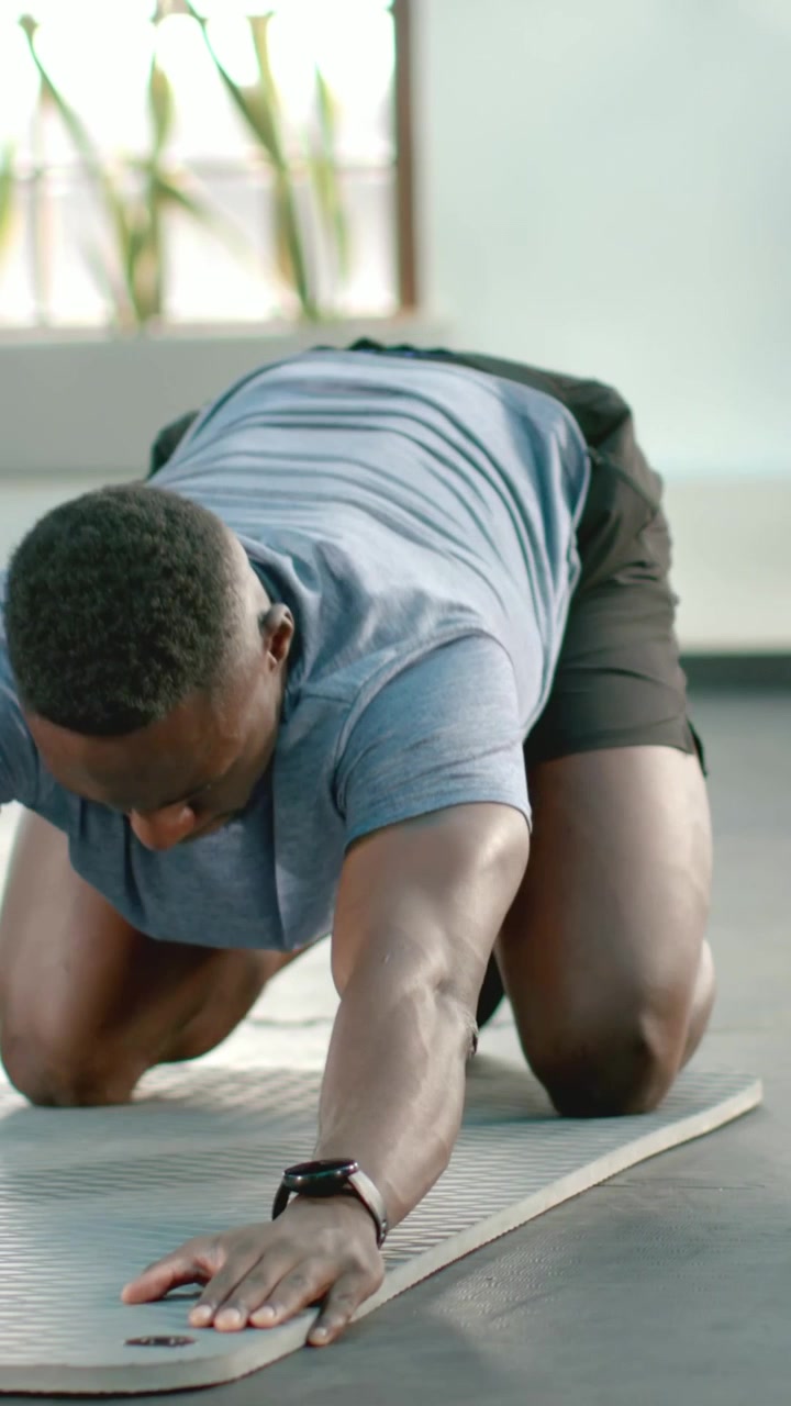 Video verticale: Coppia che inizia il riscaldamento in palestra, in grigio e blu, alternando flessioni sulle ginocchia per la forza.