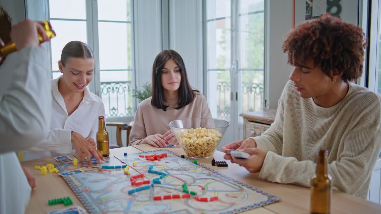 Young people playing board game together at table closeup. Man shuffling cards