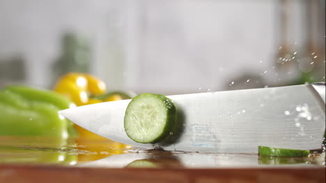 slow motion of cucumber sliced with a knife on wooden board in a kitchen