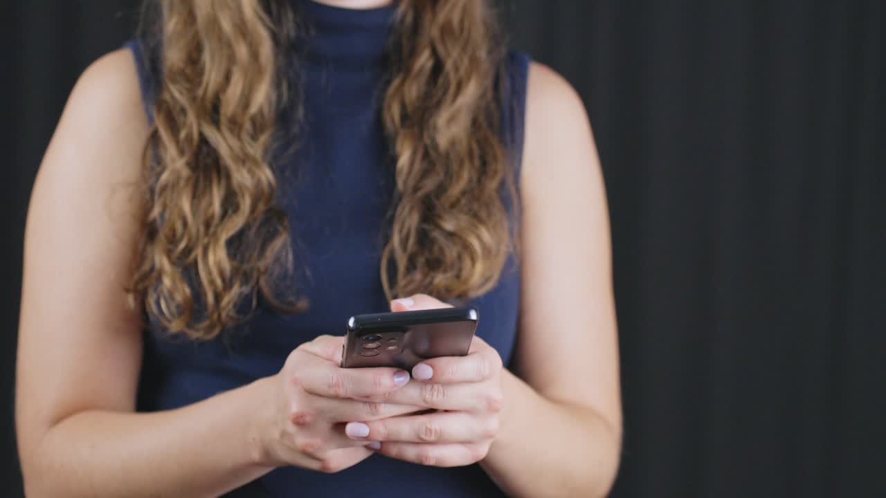 Donna che tiene uno smartphone e digita un messaggio SMS con un primo piano per un concetto di lifestyle