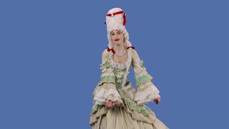 portrait of courtier lady in white vintage lace dress and wig is dancing merrily. young woman posing in studio with blue screen background. slow motion