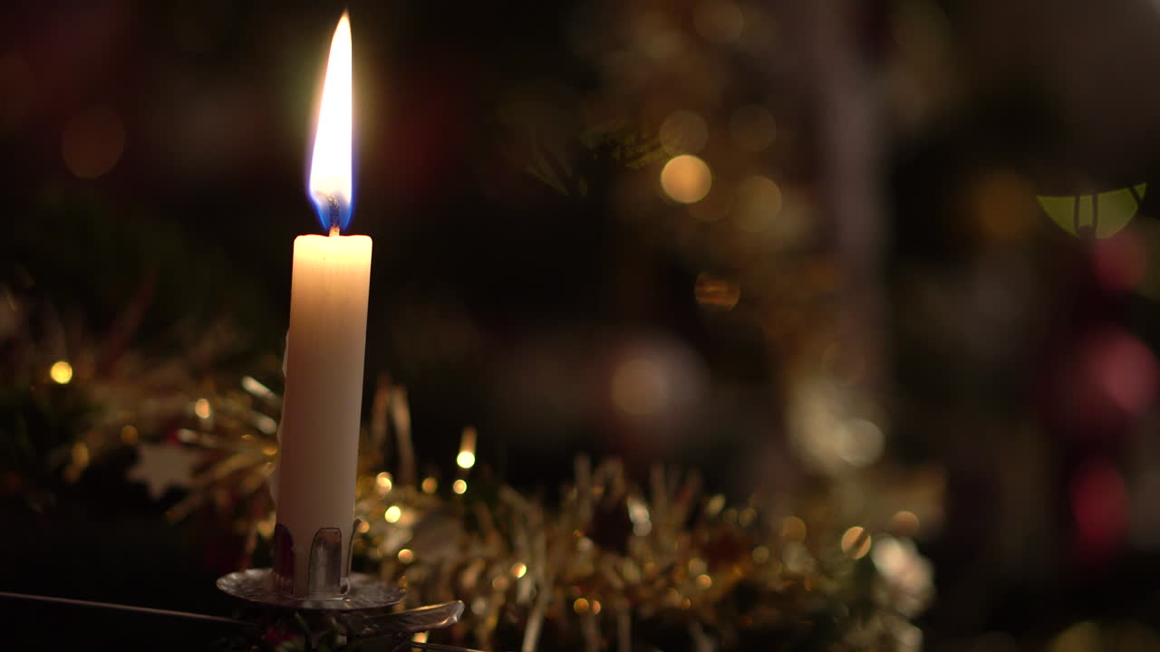 Blowing out a candle, mounted on a christmas tree in 4K.