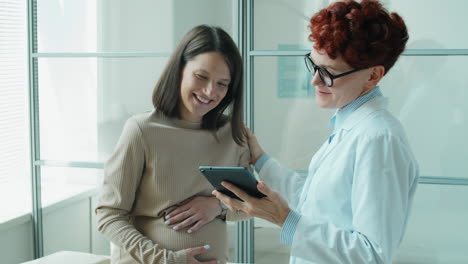 Médico-Que-Usa-Tableta-Durante-La-Consulta-Con-Una-Mujer-Embarazada