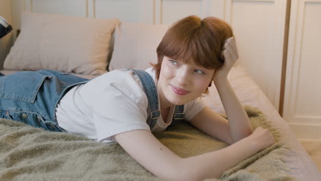 girl lying on the bed in bedroom smiling and looking at camera