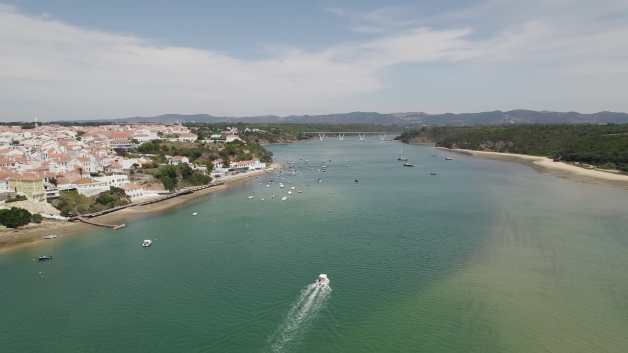 Vista aerea con vista sulle barche sul fiume Mira a Vila Nova de Milfontes, Portogallo soleggiato - ripresa inversa, da drone.