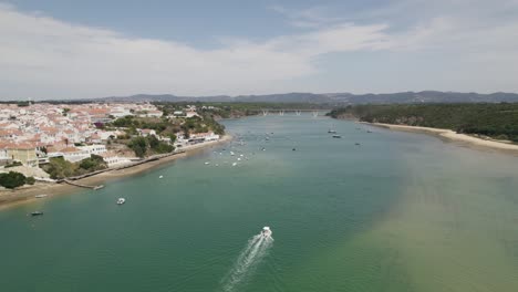 vista aérea con vistas a los barcos en el río mira en vila nova de milfontes, soleado portugal - reverso, disparo de drones