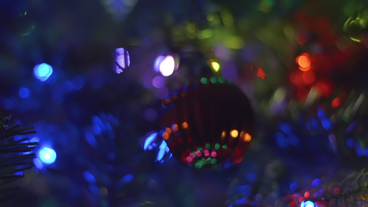 panorámica y alejamiento del adorno de bombilla rojo y texturizado con luces bokeh estables y multicolores en un árbol de navidad