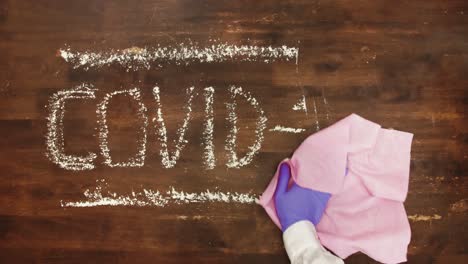 Covid-19-sign-sprayed-with-disinfectant-and-erased-with-pink-wipe