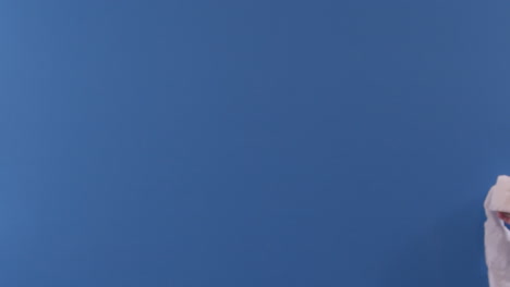 una mano arroja un rollo de papel higiénico frente a una pantalla azul