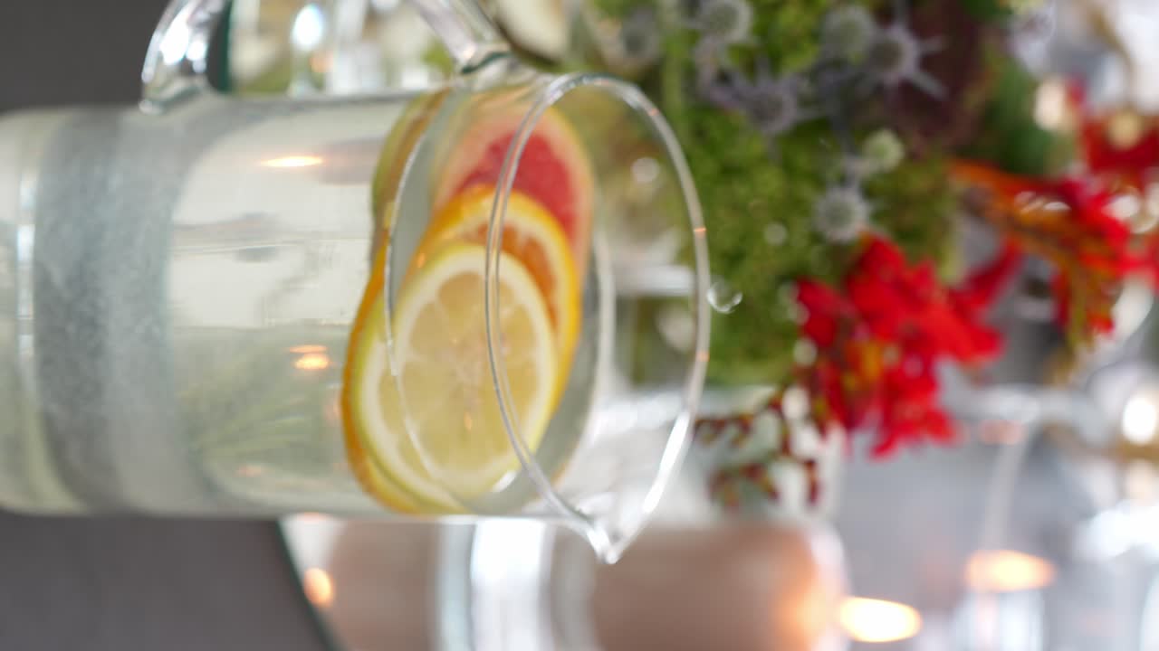 jarra de agua y adorno de ramo de flores en una mesa de comedor fina, vertical