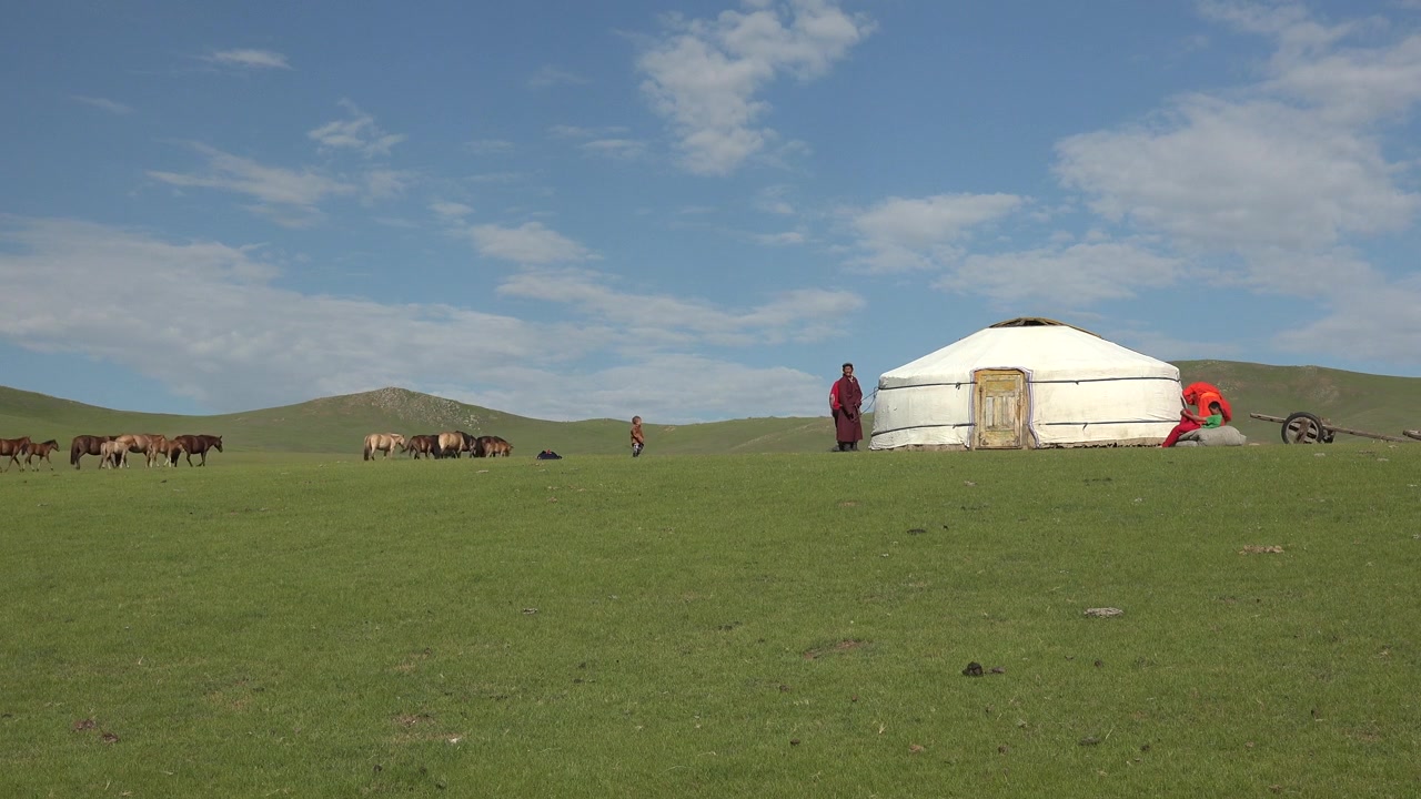 Mongolsk nomadefamilie står udenfor traditionel jurte på græsland