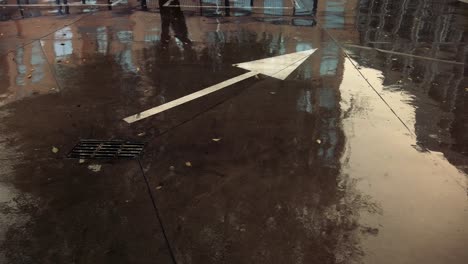 un signo de flecha en el piso de concreto bajo la lluvia