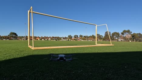 Blick-Auf-Eine-Drohne,-Die-Abhebt-Und-Durch-Ein-Fußballtor-Und-über-Das-Spielfeld-Fliegt