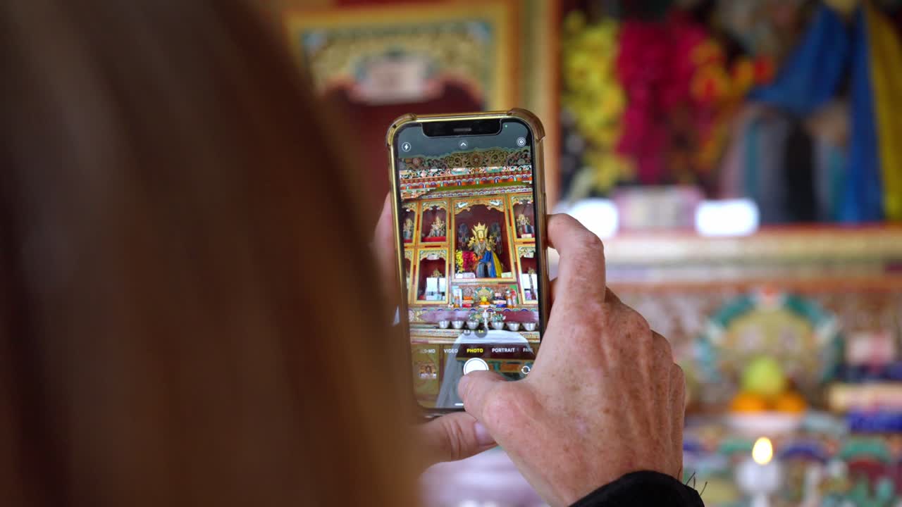 un turista captura un colorido santuario del monasterio en el interior usando una cámara de teléfono inteligente