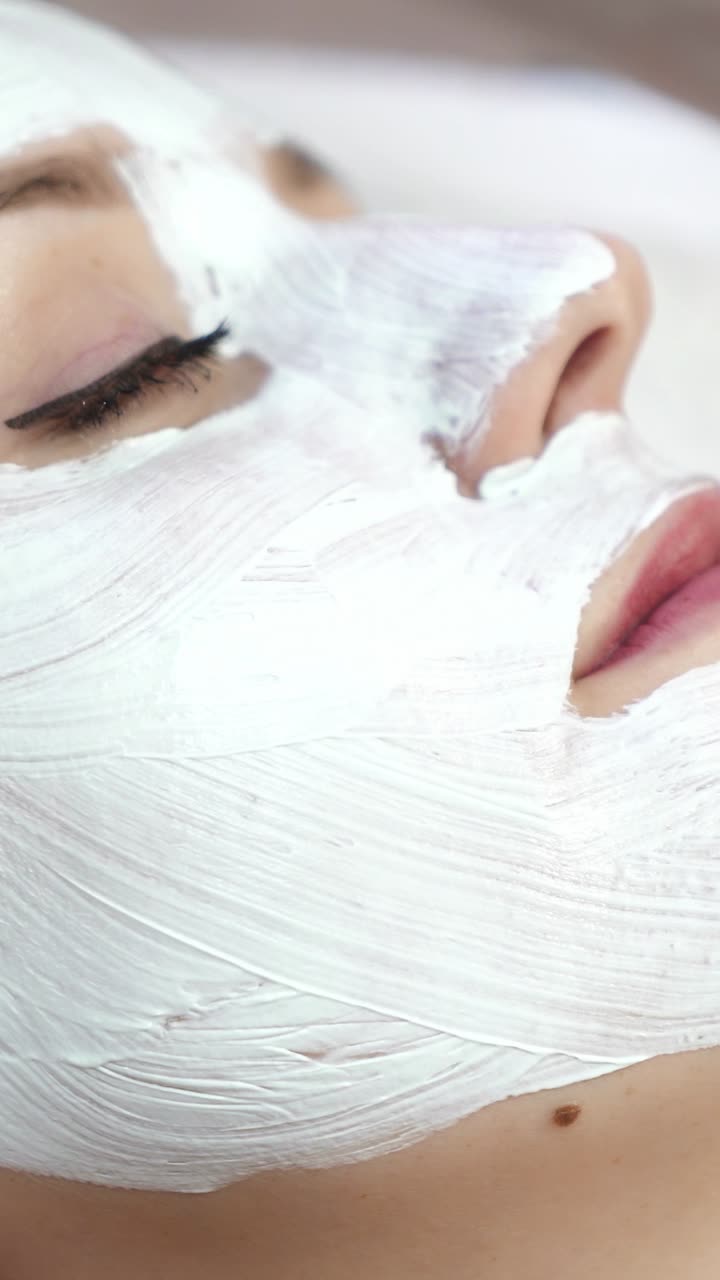 Pelle secca del viso e cura del corpo. Estetista applica una maschera cosmetica sul viso di una donna