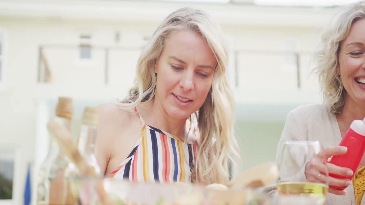 Happy caucasian family having dinner and drinking wine in garden