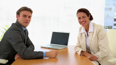 Business-people-shaking-hands-at-desk